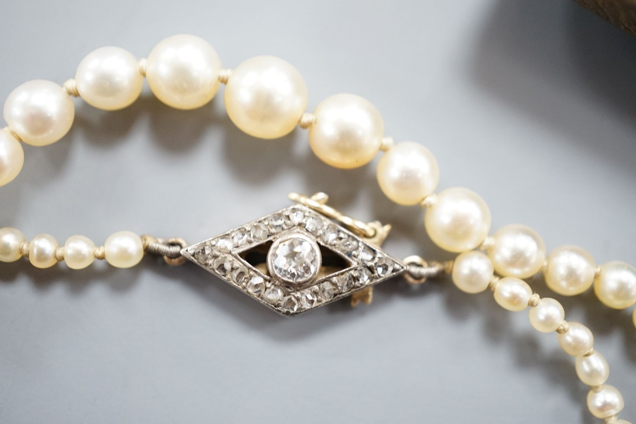 A single strand graduated seed pearl necklace, with yellow metal and diamond set clasp 42cm and a cased pair of similar Austro Hungarian ear clips.